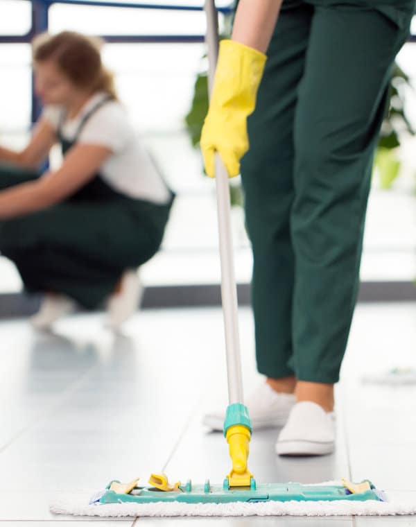 Close-up of person with yellow gloves cleaning the floor by using mop